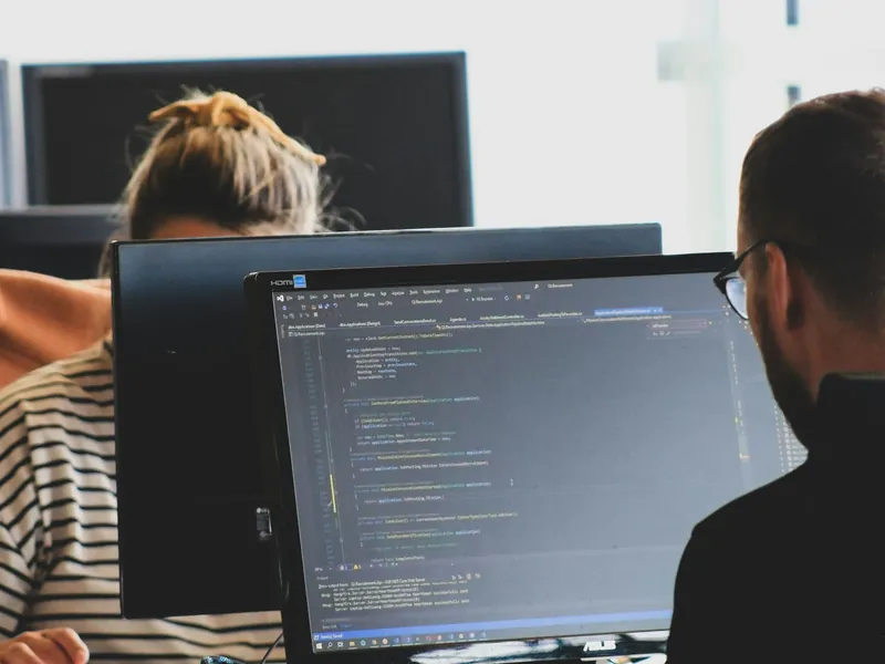 Two engineers reviewing code together on a large monitor