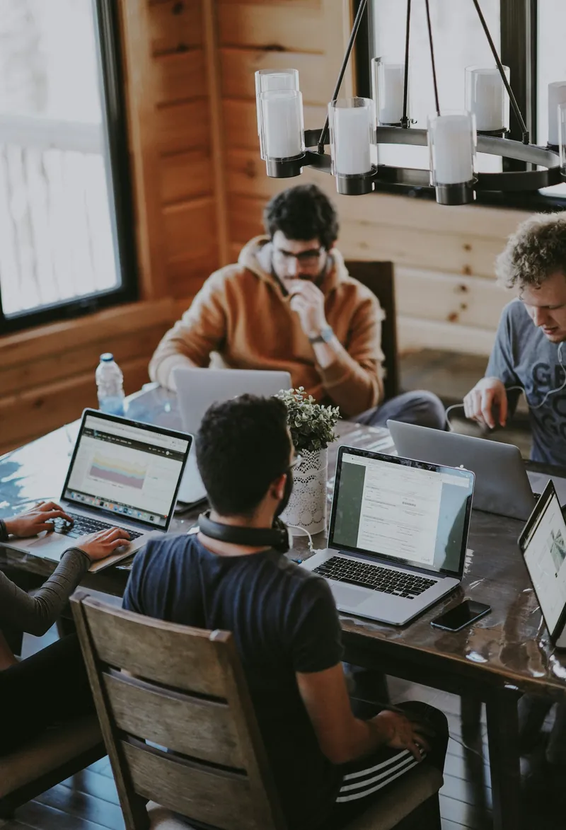 A software team working on laptops around a wooden table